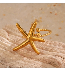 Détail macro d'une bague étoile de mer dorée sur pierre naturelle avec fond de sable
