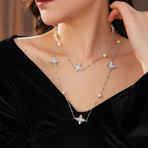 Gros plan d'un collier de perles double épaisseur avec pendentif croix serti de diamants