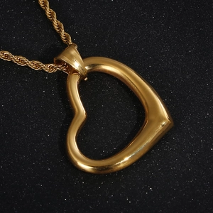 Close-up of polished gold heart-shaped pendant necklace on a black sparkling background