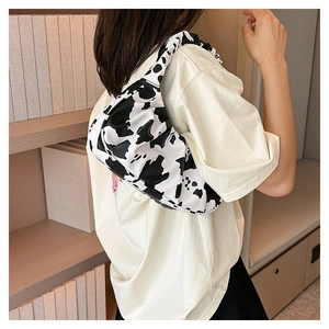 Fashionable cow print pleated cloud bag worn by a model in a casual lifestyle setting