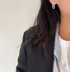 Detail shot of a silver smiling face pendant necklace and iconic link earrings on a model