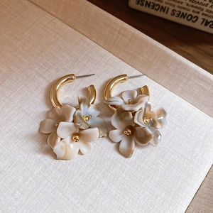 Detail of C-shaped flower earrings with marble resin texture and gold-plated metallic finish