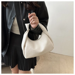 Detail of white knotted shoulder bag with woven texture on black leather jacket