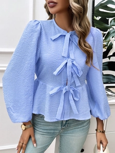 Detail of blue plaid blouse featuring puff sleeves and three front bow ties for women