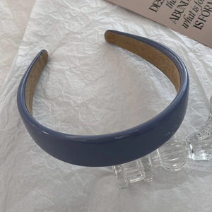Detail of dark blue faux leather headband with soft brown velvet lining on a white backdrop