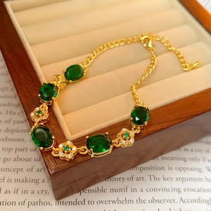 Close-up of emerald flower bracelet draped on a vintage wooden box with paper