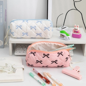 Detail of quilted cotton pencil cases with bow patterns and zipper closure in a desk setting