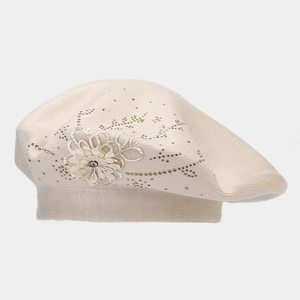 Dettaglio del berretto in maglia crema con ricamo floreale in rete e strass brillanti