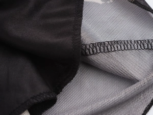Close-up of overlock stitching detail on black and white mesh paneled dress fabric