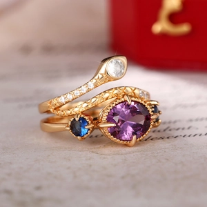 Macro detail of a golden snake ring and a vintage purple gemstone set on a book