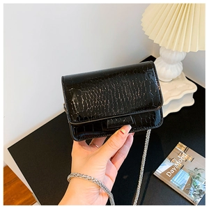 Detail of black faux crocodile leather mini bag with silver chain strap texture