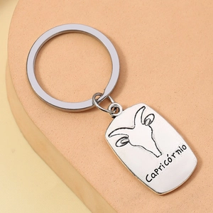 Silver Capricorn zodiac keychain with engraved goat icon and text on a stone background