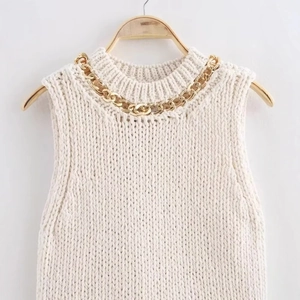 Cream sleeveless knit top featuring a bold gold chain neckline on a white background