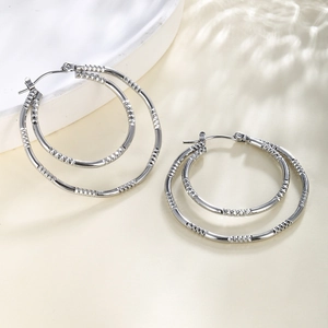 Close-up of silver double-hoop earrings with intricate diamond-cut texture and ear buckle