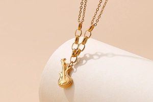 Detailed close-up of a golden guitar pendant on a double-layered O-chain necklace