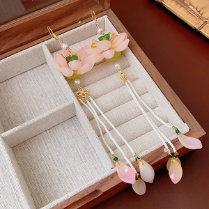 Detail of pink lotus earrings with pearl tassels in a wooden jewelry box display