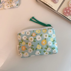 Detailed close-up of a floral cotton coin purse with zipper and green woven handle