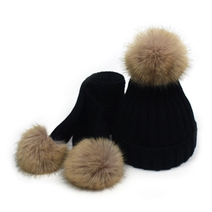 Detail of black knit winter set with soft faux fur pom-poms on hat and scarf