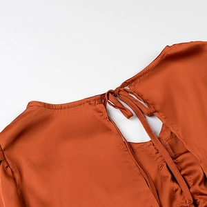 Détail du haut dos nu en satin marron rouge avec lacets croisés et découpe élégante