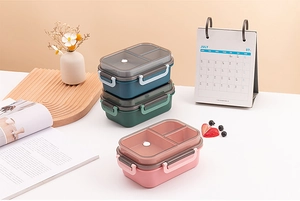Three-color bento box set with partitioned sections and transparent lids in a home setting