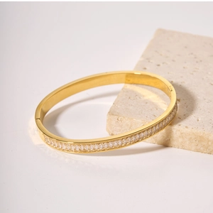 Dettaglio del bracciale in acciaio dorato con zirconi rettangolari su base di marmo