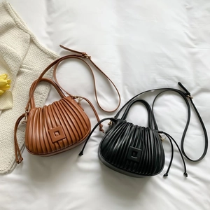 Detail of pleated bucket bags in black and caramel leather with drawstring accents