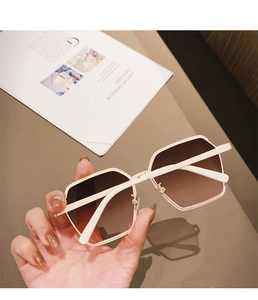 Detailed view of hexagonal cream frame sunglasses with brown gradient lenses and thick acetate