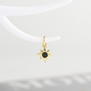 Detail of a gold eight-pointed star pendant with a centered black zircon stone