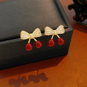 Détail de boucles d'oreilles cerise avec placage en or 18 carats et zircons blancs éclatants