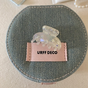 Detail shot of clear acetate hair claw clip with rhinestones on a denim accessory bag