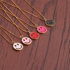 Detail of five smiley face necklaces in assorted enamel colors on a wooden background