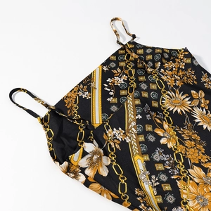 Détail de l'imprimé baroque doré et floral sur une robe en satin noir à fines bretelles