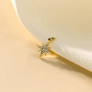 Macro shot of gold star pendant with micro-paved zircons on soft beige fabric