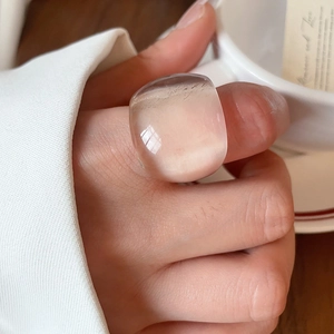 Close-up of a minimalist clear resin oval ring on model holding a coffee cup