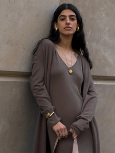 Detail shot of golden metal jewelry set paired with brown knitted cardigan and dress