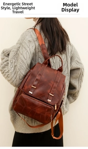 Detail eines braunen Vintage-Rucksacks mit Lederstruktur und verstellbaren Trägern