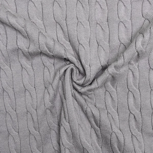 Gros plan détaillé sur la maille torsadée grise d'un pull moulant pour l'hiver