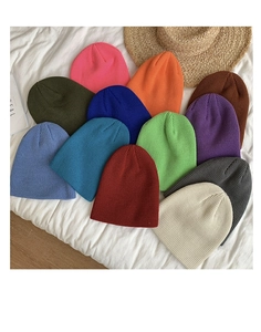 Detailed flat lay of knitted beanies in various vibrant colors on a clean white surface