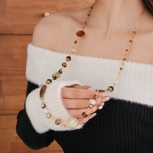 Detail of beaded long necklace with brown amber agate stones on a female model