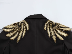 Close-up of intricate gold sequin wing embroidery on the back of a black blazer