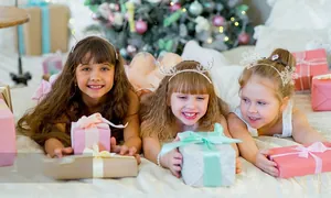 Three kids wearing Christmas headbands with HO HO HO, antlers and snowflake designs