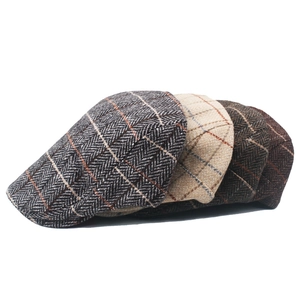 Close-up of three men's wool tweed newsboy caps with herringbone patterns in various colors