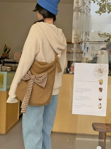 Detail of a brown fuzzy lamb wool tote bag with a checkered bow in a cozy cafe setting