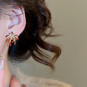 Gros plan de boucles d'oreilles feu d'artifice en émail rouge et or avec cristaux
