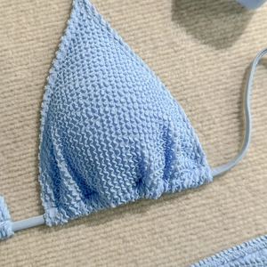 Detailed close-up of sky blue crinkle fabric on a triangle bikini top with thin straps