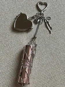 Detail of silver mesh lipstick holder keychain featuring a heart mirror and bow charm