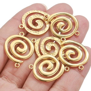 Golden stainless steel spiral vortex charms held in hand to show actual scale for DIY jewelry