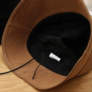 Close-up of camel suede bucket hat interior showing black lining and adjustable drawstring