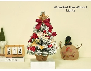 Mini Christmas tree detail with red velvet bows and golden deer on a warm festive desk