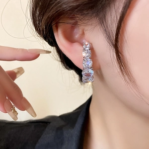 Gros plan de clous d'oreilles géométriques en zircon montrant des cristaux étincelants
